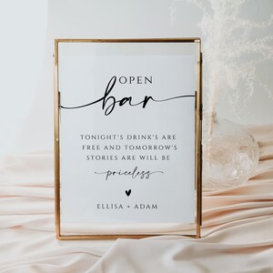 May include: A gold-framed sign with the text "OPEN bar" in a cursive font. The sign also includes the text "TONIGHT'S DRINK'S ARE FREE AND TOMORROW'S STORIES ARE WILL BE priceless" and "ELLISA + ADAM".