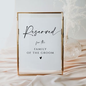 May include: A gold-framed sign with the text "Reserved for the Family of the Groom" in black lettering. A small heart symbol is below the text.