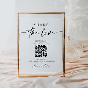 May include: A white sign in a gold frame with the text "SHARE the love" and a QR code. The text below the QR code says "PLEASE SHARE YOUR PHOTOS WITH US!" and "SCAN WITH YOUR SMARTPHONE AND UPLOAD colleen + steven".