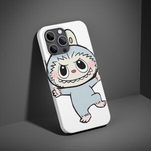 May include: White phone case featuring a cartoon monster with a light blue body, pink cheeks, and a toothy grin. The monster has large eyes and is set against a white background. The phone case has a camera cutout.