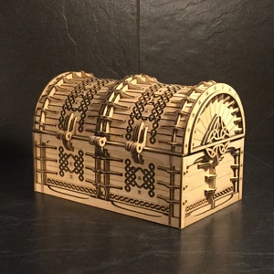 May include: A wooden treasure chest with intricate Celtic knotwork designs and a hinged lid. The chest is closed and has a decorative metal latch.