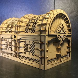 May include: A wooden treasure chest with a Celtic knot design and a hinged lid. The chest is made of light wood and has a dark brown stain.