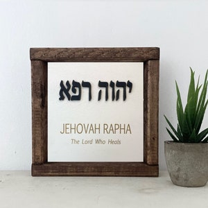 May include: A wooden framed sign with the Hebrew words "Jehovah Rapha" and the English translation "The Lord Who Heals".