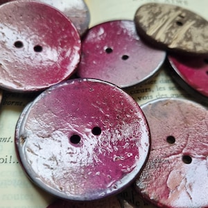 Op de afbeelding: Assortiment van ronde houten knopen met een roze en witte ombre-effect. De knopen hebben twee gaten en een getextureerd oppervlak.