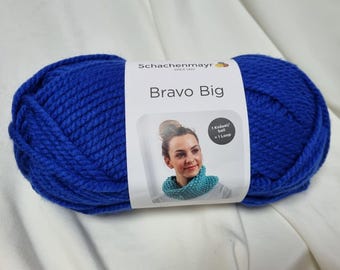 以下が含まれることがあります： Schachenmayrの「Bravo Big」と書かれた、青色の大きな毛糸玉。ラベルには、ニットのスヌードを身につけた女性が写っています。この毛糸は鮮やかな青色で、編み物や手編みのプロジェクトに最適です。