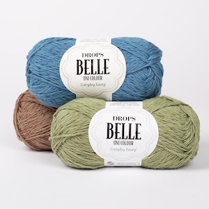 以下が含まれることがあります： 青、茶色、緑色のDrops Belle Uni Colourの毛糸が3玉。各玉にはブランド名と製品詳細が記載された白いラベルが付いています。この毛糸は、レーヨン、リネン、綿の混紡です。