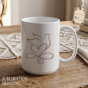 Peut inclure: Mug en c&eacute;ramique blanche avec un motif de colombe et de c&oelig;ur marron clair. La tasse a une grande anse et les mots "Sublimation Printing" sont imprim&eacute;s en bas. Une &eacute;tiquette indique "Created by Pro Art Creation".