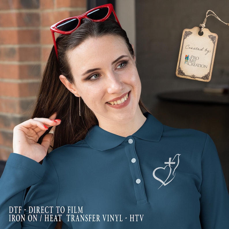 May include: Teal long-sleeve polo shirt with a white heart and cross design. The shirt has a collar and three buttons. The text "DTF - DIRECT TO FILM IRON ON / HEAT TRANSFER VINYL - HTV" is at the bottom of the image.