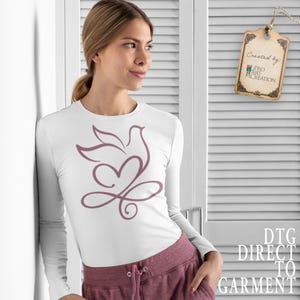 Peut inclure: T-shirt blanc &agrave; manches longues avec un motif mauve de colombe et de c&oelig;ur. Le motif comprend une colombe, un c&oelig;ur et un symbole infini. Le t-shirt est associ&eacute; &agrave; un pantalon de surv&ecirc;tement mauve. L'&eacute;tiquette indique "Created by: Pro Art Creation".