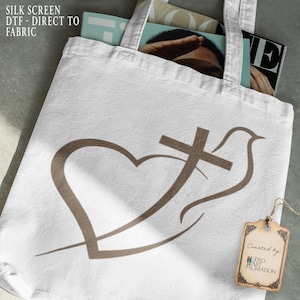 May include: White tote bag with a brown heart, cross, and dove design. The bag contains magazines and has a tag that says "Created by: Pro Art Creation". The words "SILK SCREEN DTF - DIRECT TO FABRIC" are printed on the bag.