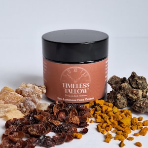 May include: A 2 oz jar of Timeless Tallow Luminous Face Cream. The jar is black with a brown label that says "Timeless Tallow" and "Bringing Back Tradition". The jar is surrounded by various ingredients, including dried rose hips, turmeric, and frankincense.