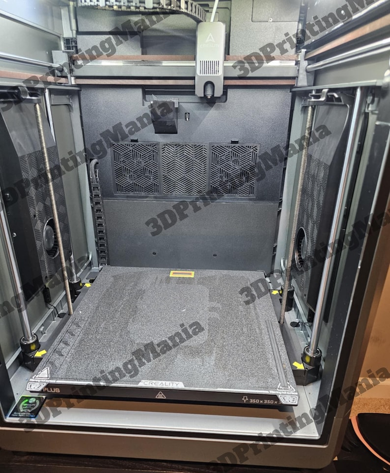 May include: A close-up view of the interior of a 3D printer. The printer has a black and gray build platform with a textured surface. The platform is labeled "CREALITY" and "350 x 350".