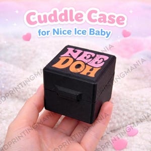 May include: A black square case with the text "NEE DOH" in pink and orange. The case is labeled "Cuddle Case for Nice Ice Baby". The case is held in a hand.