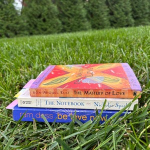 A pile of books sitting in the grass with the gradient bookmarks in them.