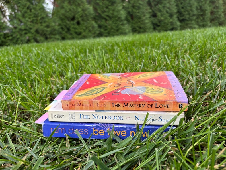 A pile of books sitting in the grass with the gradient bookmarks in them.