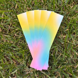 A handful of the gradient bookmarks sitting on some grass.