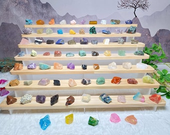 May include: A wooden display stand with seven shelves, each holding a variety of colorful and textured gemstones. The stand is on a white surface with a few loose gemstones scattered around it.