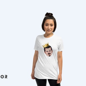 May include: A white t-shirt with a cartoon image of a man wearing a gold crown. The man has a mustache and a goatee.