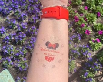 May include: A red and white temporary tattoo with a Mickey Mouse head and the text "Drinking Around the World" with a circle of abbreviations around the outside. The tattoo is on a person's arm.