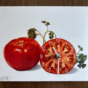 May include: A square wall clock featuring a white background with a whole red tomato, a sliced tomato cross-section serving as the clock face with white numbers, and green parsley sprigs. The word DAVID is printed in the bottom left corner.