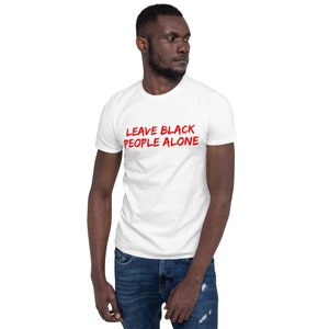 Puede incluir: Camiseta blanca con el texto "LEAVE BLACK PEOPLE ALONE" en letras rojas.