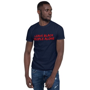 Puede incluir: Una camiseta azul marino con el texto "LEAVE BLACK PEOPLE ALONE" en letras rojas.