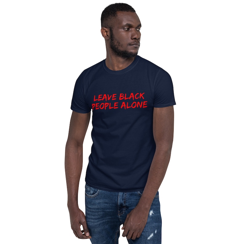 Puede incluir: Una camiseta azul marino con el texto "LEAVE BLACK PEOPLE ALONE" en letras rojas.