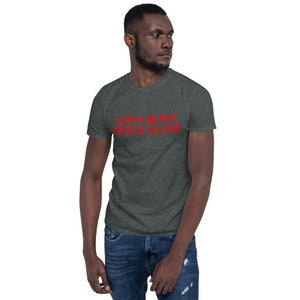 Puede incluir: Una camiseta gris oscuro jaspeada con el texto "LEAVE BLACK PEOPLE ALONE" en rojo.
