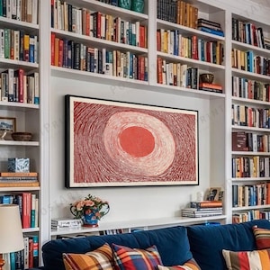 May include: A cozy living room with a navy blue sofa, colorful throw pillows, and a striped rug. A large abstract painting hangs above the sofa, and bookshelves line the walls. A round wooden coffee table holds books and candles, and a paper lantern hangs from the ceiling.