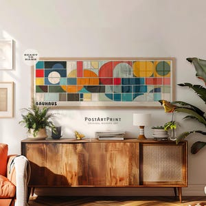 May include: A rectangular wall art print featuring a geometric Bauhaus design with a grid of colourful circles and squares in red, blue, yellow, and teal. The print is framed in light wood and includes the text "BAUHAUS" in the bottom left corner.