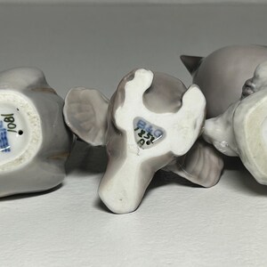 May include: Three gray ceramic bird figurines with visible markings on the bottom. The figurines are in various poses, with one lying on its side. The markings include text and a crown symbol.