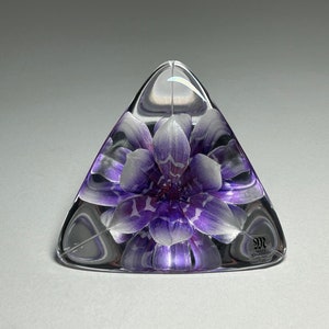 May include: A clear glass pyramid with a purple and white flower inside. The pyramid has a small label on the bottom that reads "James Powell Crystal."