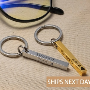 May include: Two silver keychains with engraved bars. One bar reads "XVII.MMVI Forever" with a small deer symbol. The other bar reads "02.07.2018 Love" with a heart symbol.