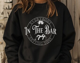 May include: Black sweatshirt with a white circular graphic that reads "EVERYBODY IN THE BAR GETTING TIPSY". The graphic includes two beer mugs and a person lying on a bar. The sweatshirt is a crew neck style.