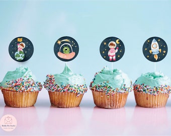 May include: A row of cupcakes with blue frosting and colorful sprinkles. Each cupcake has a decorative topper with an outer space theme, including an astronaut, an alien, and a rocket ship. The background is a gradient of blue and pink.