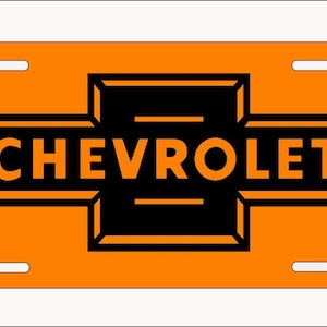 May include: Orange and black license plate featuring the Chevrolet logo. The logo is a black bowtie with the word "CHEVROLET" in white letters.