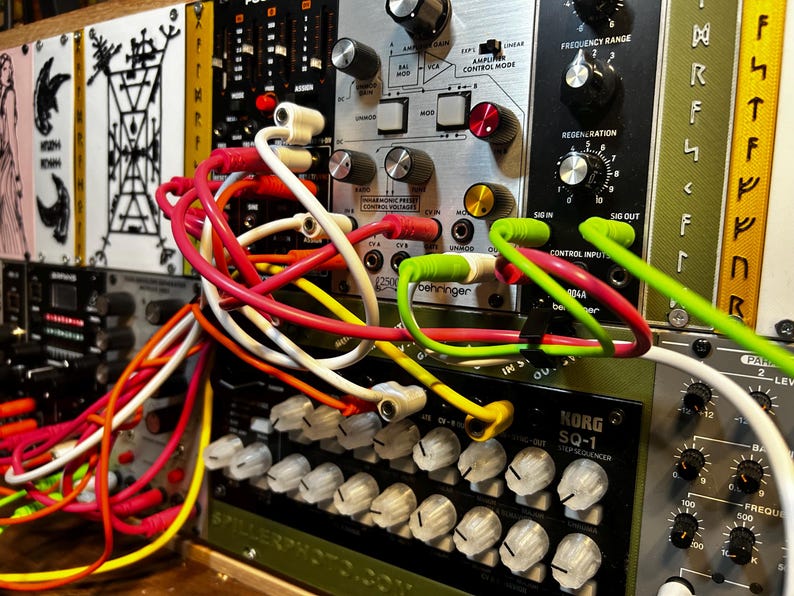 Peut inclure: Gros plan sur un synth&eacute;tiseur modulaire avec divers modules et c&acirc;bles de raccordement color&eacute;s. Les modules comportent des boutons, des interrupteurs et des &eacute;tiquettes textuelles. Des c&acirc;bles rouges, blancs, jaunes et verts relient les modules.