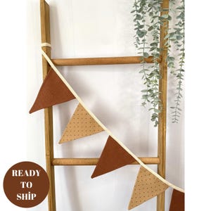 May include: A brown and tan fabric bunting with white trim and polka dots hanging on a wooden ladder. The bunting has the text "READY TO SHIP" on a red circle.