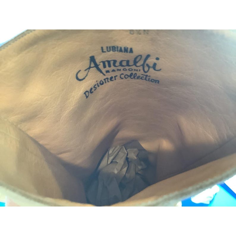 May include: Interior view of a light tan leather boot. The words "LUBIANA Amalfi RANGONI Designer Collection" are printed in dark blue script inside the boot. The boot is empty except for some crumpled paper.