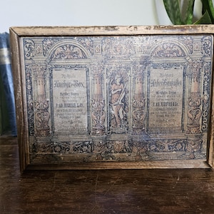 May include: A rectangular wooden box featuring a vintage label with architectural illustrations, a central figure, and text including Richter's Anchor Box and Ankerbaukasten. The label displays ornate columns and decorative patterns in muted tones.