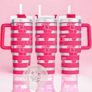 May include: Three pink insulated tumblers with white and pink striped patterns. Each tumbler features a handle, a lid with a straw, and a design of cherries and hearts. The tumblers are from Poppy & Pine Company.