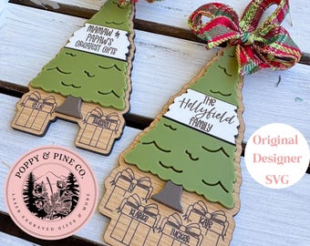 May include: Two wooden Christmas tree ornaments with green tree tops and gift-shaped bases. One reads "Mamaw & Papaw's Greatest Gifts" and the other "The Hollyfield Family." Each has a colorful plaid ribbon and personalized names.