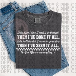 Può includere: T-shirt grigio scuro con testo bianco: "Se il posto più alto che raggiungo è ai Tuoi piedi, ALLORA HO FATTO TUTTO. Se la cosa migliore che ho visto è la Tua gloria, ALLORA HO VISTO TUTTO. Dio, tu sei il mio tutto." La maglietta è su jeans blu.