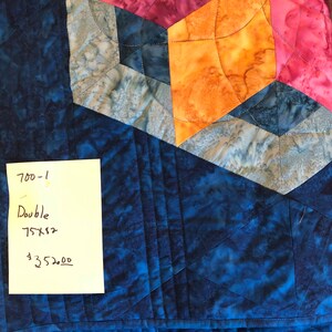 May include: A blue, gray, orange, and pink quilt with a handwritten note that says "700-1 Double 75x82 $352.00"