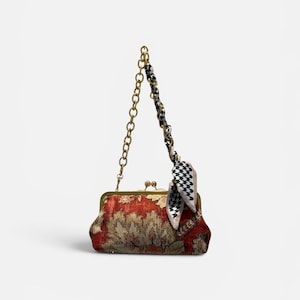 May include: A vintage-style handbag with a gold chain strap and clasp. The bag features a red and beige floral pattern and is accented with a black and white checkered scarf. The bag is a stylish accessory.