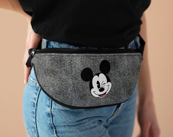 May include: A gray denim fanny pack with a black zipper and a black trim. The fanny pack has a cartoon image of Mickey Mouse winking on the front.