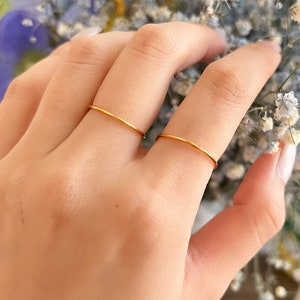 以下が含まれることがあります： 人の指に2つの細い金のリング。リングはシンプルで繊細です。