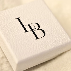 Puede incluir: Caja blanca con las letras "LB" impresas en negro.