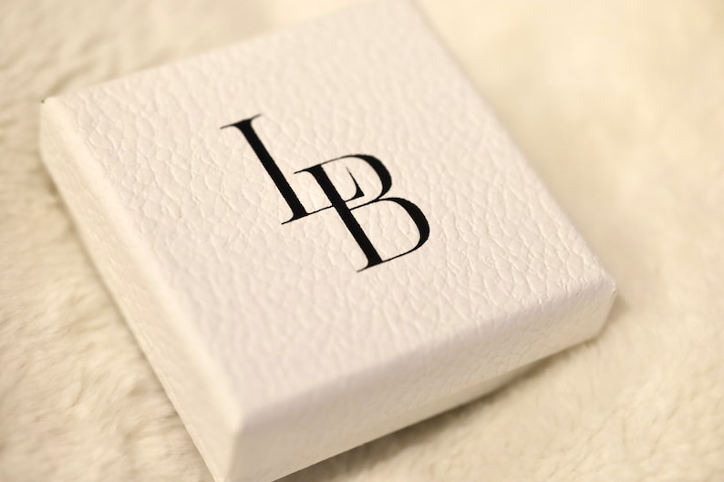 Puede incluir: Caja blanca con las letras "LB" impresas en negro.
