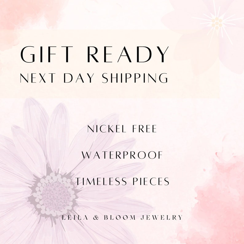 Puede incluir: Un fondo de acuarela rosa y blanco con una margarita blanca. El texto "GIFT READY NEXT DAY SHIPPING" est&aacute; en la parte superior de la imagen. El texto "NICKEL FREE WATERPROOF TIMELESS PIECES LEILA & BLOOM JEWELLERY" est&aacute; en la parte inferior de la imagen.